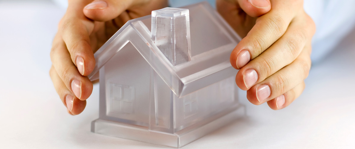 Manos protegiendo una casa de cristal que simboliza la seguridad del vidrio CLIMALIT®