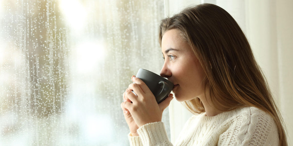 Imagen de mujer mirando lluvia en ventana